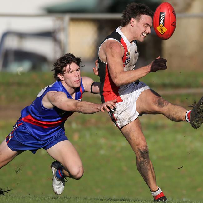 Koroit’s James Gow gets his kick away despite a lunging tackle from a Terang-Mortlake opponent.