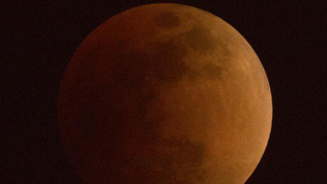 The moon turns a reddish hue as it passes through the earth's shadow during a lunar eclipse as seen in Beijing. Picture: AP