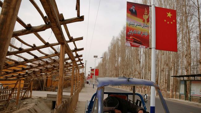 A poster showing Chinese President Xi Jinping lines a road in the Xinjiang Uighur Autonomous Region. Picture: Reuters