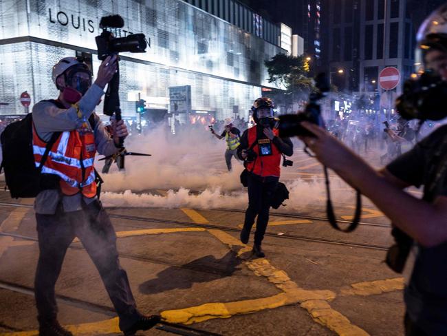 Reporters work as police fire tear gas to disperse people in Central district during Halloween in Hong Kong. Picture: AFP