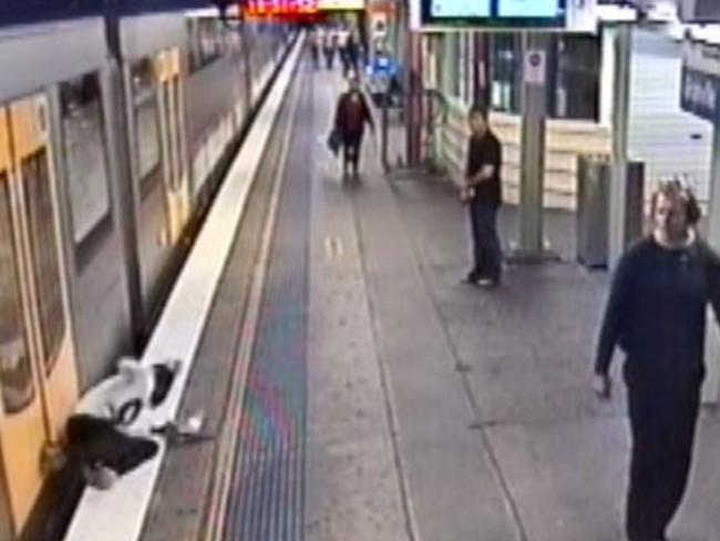 He falls onto the platform and very nearly into the gap between it and the moving train.