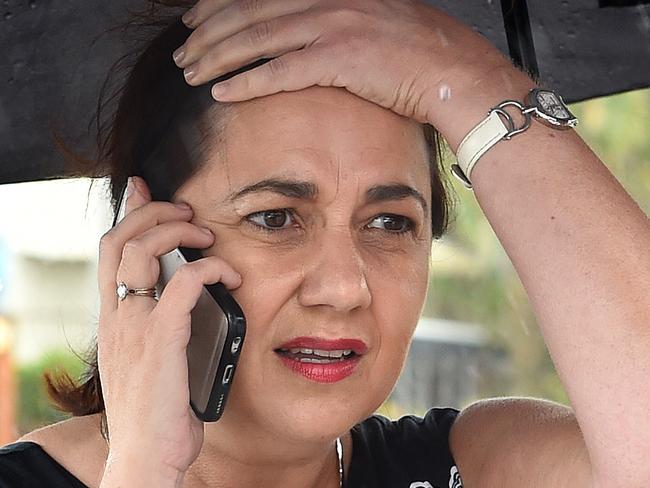 Queensland Premier Annastacia Palaszczuk is shielded from the rain as she takes a phone call during an engagement at Point Danger on the Gold Coast, Tuesday, March 8, 2016. Palaszczuk says she is prepared to call an early election after government MP Rob Pyne quit her Labor party on Monday night following months of complaints about the party system. (AAP Image/Dave Hunt) NO ARCHIVING