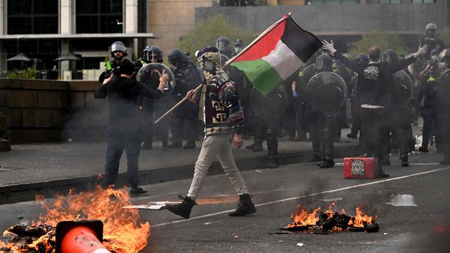 A man waves a Palestinian flag as protesters confront police outside the Land Forces 2024 arms fair in Melbourne on Wednesday. Picture: AFP