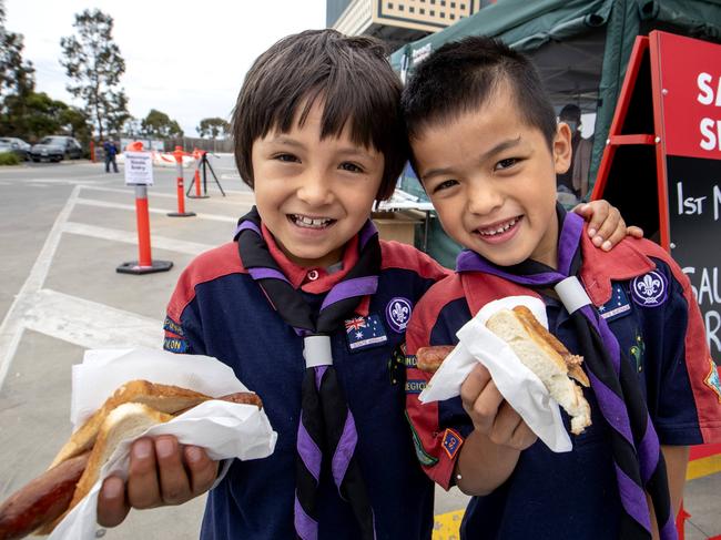 MELBOURNE, AUSTRALIA - NewsWire Photos December 5 2020: Boy Scouts Casey Hungerfield, 6 and Louis Lai, 6, get into a sausage in bread  at Bunnings in Maribyrnong on Saturday morning  as the Bunnings sausage sizzle is finally making a return in Melbourne after an eight-month absence. Picture: NCA NewsWire / David Geraghty