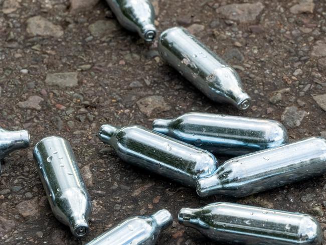 Nitrous oxide cartridges lay empty on the ground in a rural area after being used as drugs for human consumption