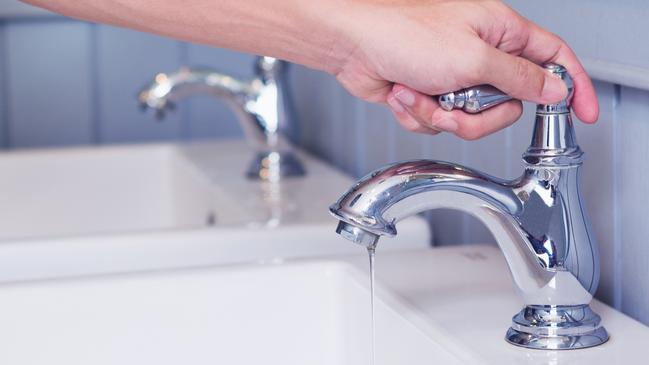 hand man opening silver faucet or water tap with white washing sink in public toilet.