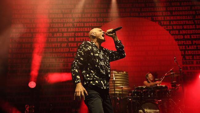 Midnight Oil singer Peter Garrett performing beneath a banner displaying text from the Uluru Statement From The Heart, while flanked by drummer Rob Hirst on the band’s 2017 world tour. Picture: Awais Butt