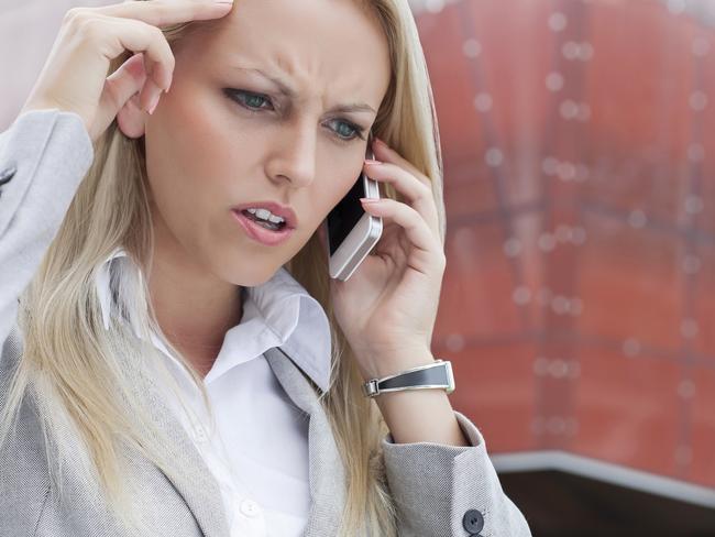 Close-up of angry businesswoman conversing on cell phone against office building