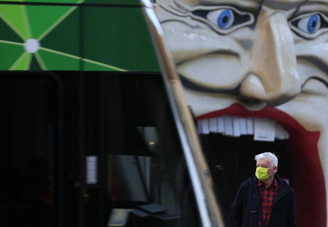 A man wearing a facemask catches a tram in St Kilda. Victoria recorded 177 new cases overnight. Picture: Getty