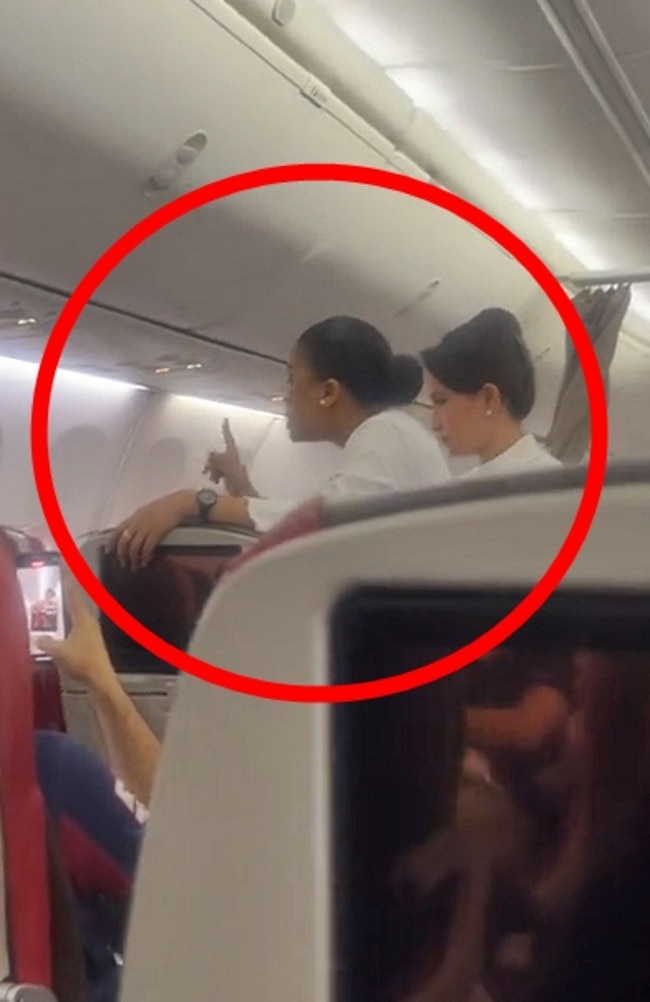 A flight attendant talking to a passenger who refuses to put on her seatbelt. Picture: Jam Press