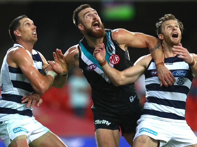 GOLD COAST, AUSTRALIA - AUGUST 14: Charlie Dixon of the Power (center) is wrapped up by Geelong defense during the round 12 AFL match between the Geelong Cats and the Port Adelaide Power at Metricon Stadium on August 14, 2020 in Gold Coast, Australia. (Photo by Jono Searle/AFL Photos/via Getty Images)