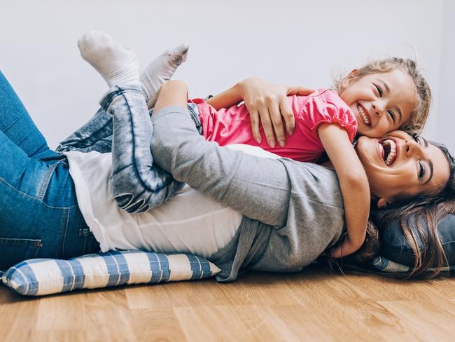 Happy mother and daughter playing and embracing on the floor