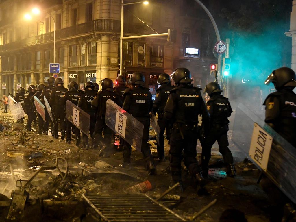 Police walk over debris in Barcelona, after violence escalated during clashes with radical separatists. Picture: AFP