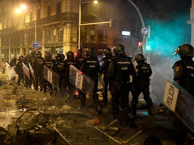 Police walk over debris in Barcelona, after violence escalated during clashes with radical separatists. Picture: AFP