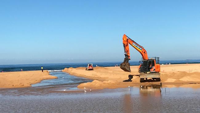 An excavator at work at the entrance to Narrabeen Lagoon at North Narrabeen Beach to create a channel to the sea. Picture: Manly Daily