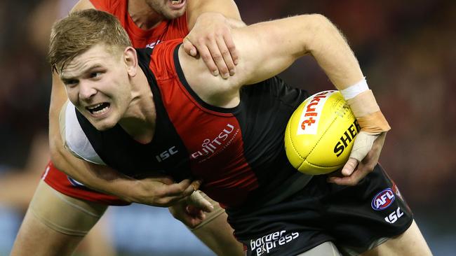 Essendon’s Michael Hurley clears by hand as he is tackled by Sydney’s Nic Newman. Picture: Michael Klein