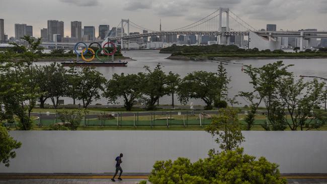 The Olympic Rings loom in the background as a man runs near the Odaiba Marine Park Olympic venue in Tokyo, Japan. Picture: Yuichi Yamazaki/Getty Images