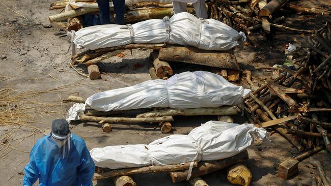 A health worker walks past the funeral pyres of COVID-19 victims during a mass cremation in New Delhi. Picture: Adnan Abidi/Reuters