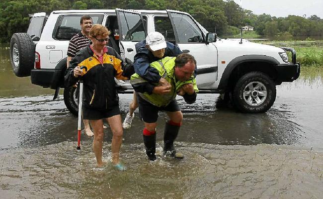 Rick O’Connor helps 94-year-old Stan Dearnley, of the Central Coast, get to a waiting State Emergency Service boat on Woodford Island. Picture: Lynne Mowbray