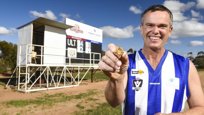 Hard won: Warrick Grey with the premiership medallion won by his grandfather, Stan Grey, in 1919. The grand final scores from the match that was finally completed are on the scoreboard behind him. Picture: Dannika Bonser