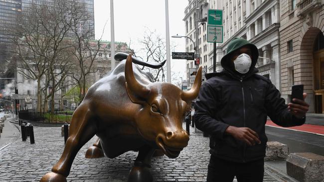 A man wearing a face mask takes a selfie at the Charging Bull statue near the New Stock Exchange. Picture: AFP