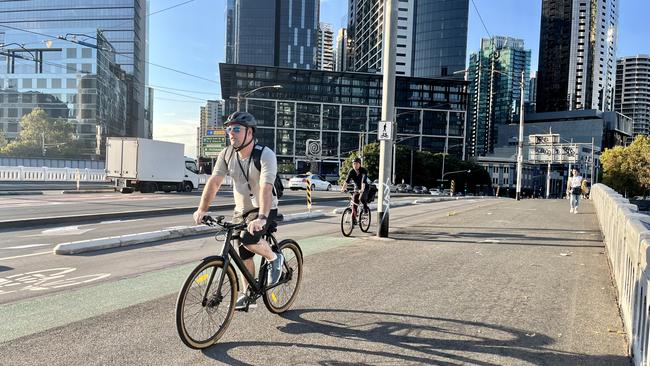 A cyclist rides on the footpath despite the provision of a bike lane on Queens Bridge.