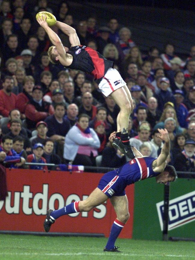 Essendon’s Gary Moorcroft flies high over an unsuspecting Brad Johnson in 2001.