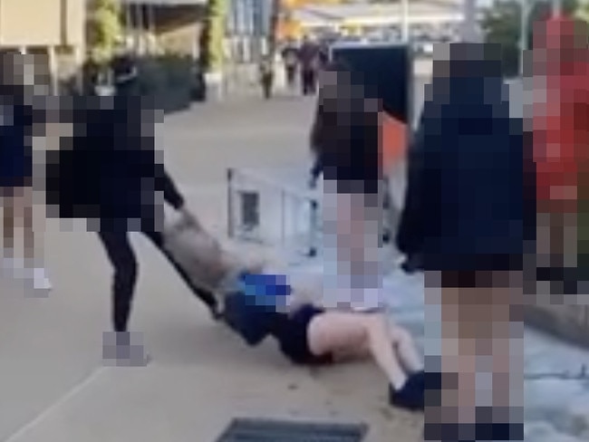 Police have arrested and charged two teenage girls with aggravated assault after a video was posted to social media showing a girl being kicked, punched and dragged – while others watched and filmed., The 51-second clip, taken outside Elizabeth Shopping Centre on Thursday night, was posted to an Instagram page with more than 1000 followers which is filled with similar videos of physical altercations between teenagers and children.