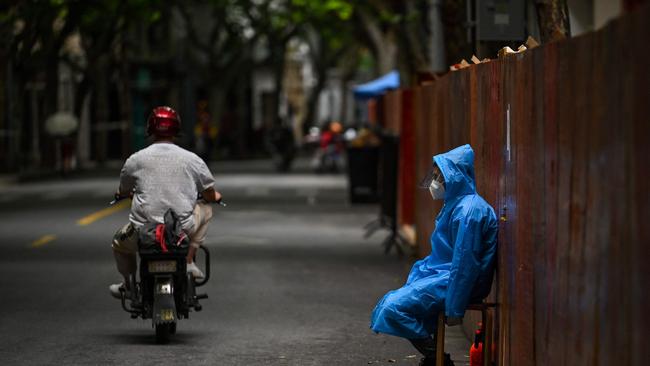 A worker sits next to a fence erected to close a residential area under Covid-19 lockdown in the Huangpu district of Shanghai. Picture: AFP.