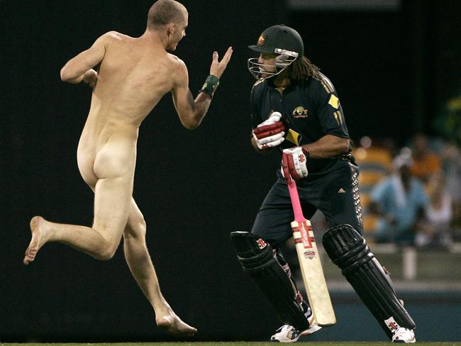 05/03/2008: Australia's Andrew Symonds, foreground, prepares to check a pitch invader to the ground during the second final of their tri-nations one day international cricket series against India at Brisbane, Australia, Tuesday, March 4, 2008. India made 258 in their innings. (AP Photo/Rick Rycroft)