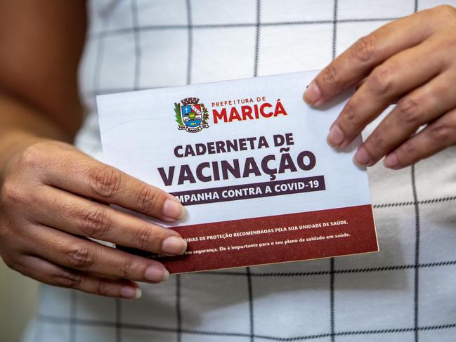 A Brazilian health worker holds her vaccination card after receiving first dose of AstraZeneca vaccine. The jab will be suspended for pregnant women. Picture: Buda Mendes/Getty Images