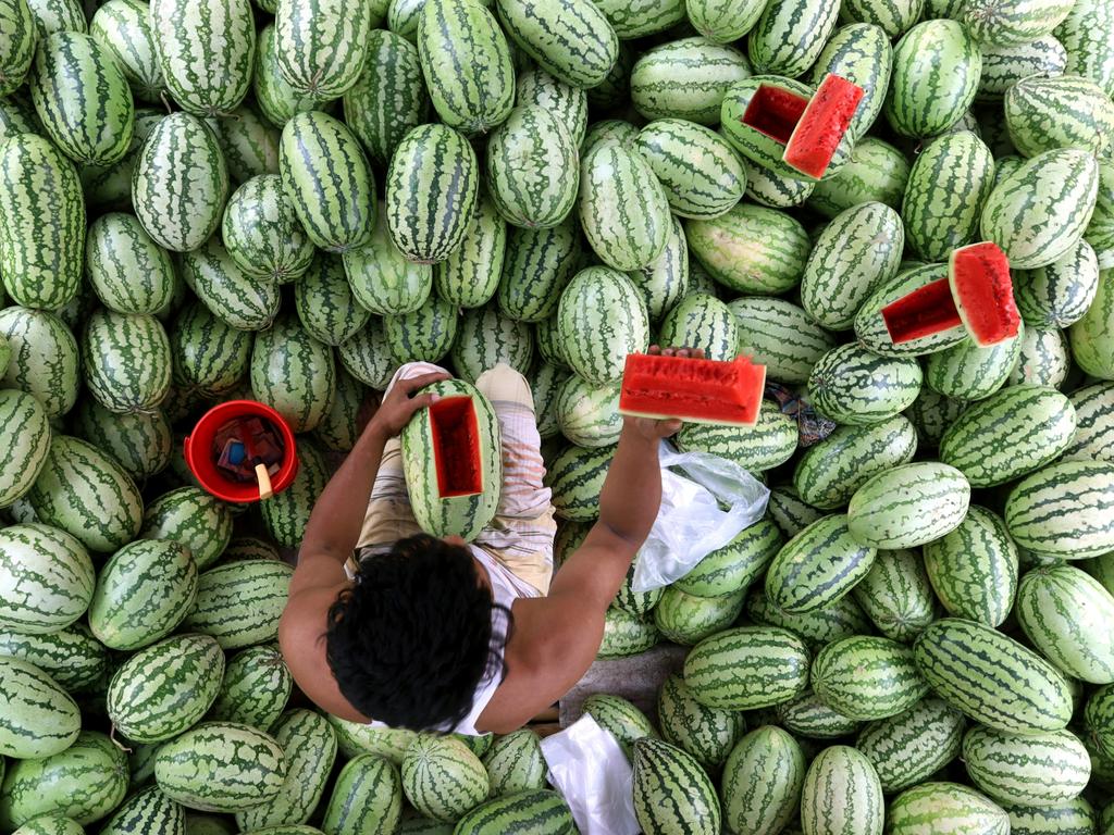 A watermelon seller demonstrates the freshness of a watermelon to a customer in Tongi Bazar, Bangladesh. Picture: Syed Mahabubul Kader/Pink Lady® Food Photographer of the Year