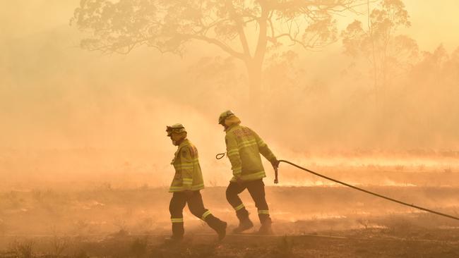 Firefighters defend a property from a bushfire at Hillville near Taree, 350km north of Sydney on Tuesday. Picture: Peter Parks/AFP