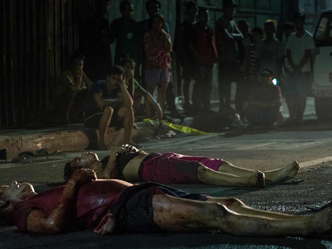 Residents gather near two dead bodies lying on the road after they were gunned down by unidentified men riding a motorcycle in Manila on October 3, 2016. Picture: Noel Celis