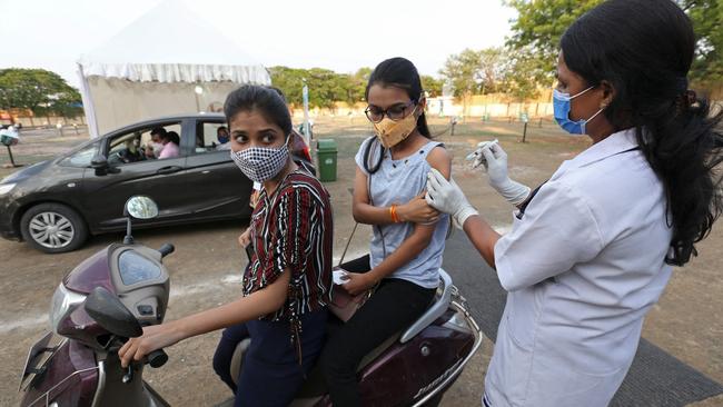 A medical worker inoculates a girl sitting on a bike with a dose of the Covishield Covid-19 coronavirus vaccine in Bhopal, India. Picture: AFP