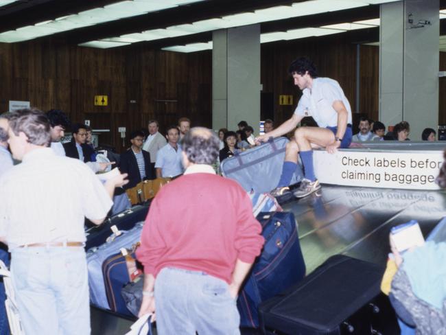 An airport worker helps travellers with their luggage on the baggage carousel.