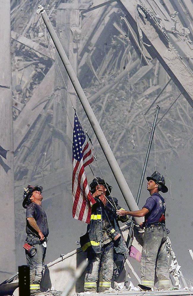 Brooklyn firefighters George Johnson, left, Dan McWilliams, centre, and Billy Eisengrein, right, raise a flag at the World Trade Centre. Picture: AP Photo/ Copyright 2001 The Record