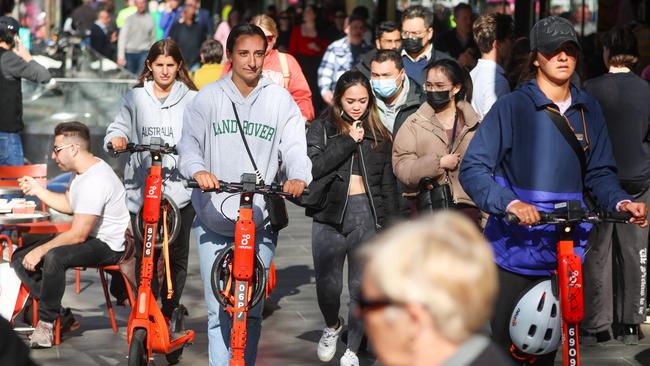 Helmetless e-scooter riders on the Elizabeth Street footpath in Melbourne. Picture: Brendan Beckett