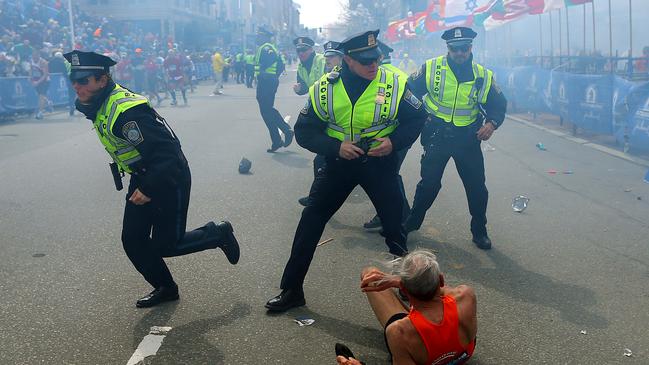 Bill Iffrig, 78, lies on the ground as police officers react to a second explosion at the finish line of the Boston Marathon. Picture: AP