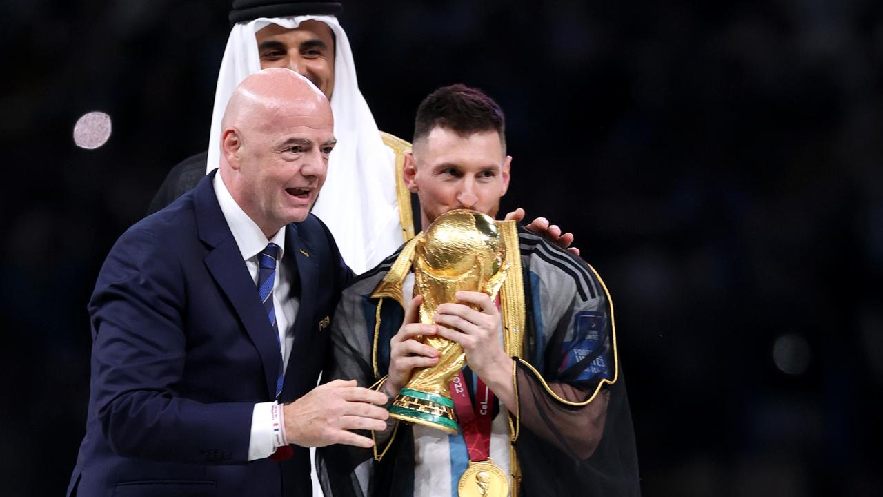 LUSAIL CITY, QATAR - DECEMBER 18: Lionel Messi of Argentina kisses the FIFA World Cup Qatar 2022 Winner's Trophy as Gianni Infantino, President of FIFA, and Sheikh Tamim bin Hamad Al Thani, Emir of Qatar, look on during the FIFA World Cup Qatar 2022 Final match between Argentina and France at Lusail Stadium on December 18, 2022 in Lusail City, Qatar. (Photo by Julian Finney/Getty Images)