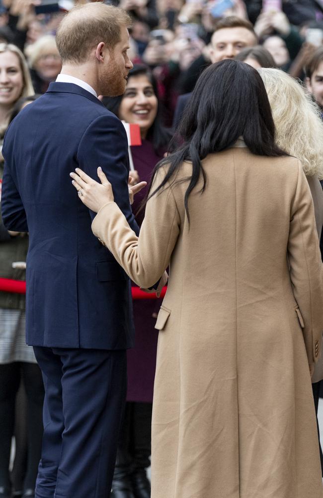 Meghan places her hand on Harry’s back as they greet fans. Picture: Mark Cuthbert/UK Press via Getty Images