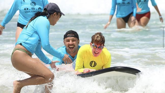 DSA volunteers helping a participant catch a wave. Photo: Disabled Surfers Australia