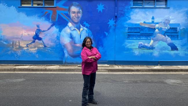 Felice Burton in front of the Macksville mural she painted of Phil Hughes