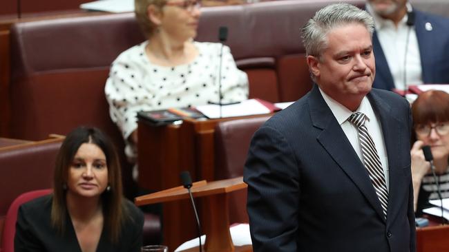 Senator Mathias Cormann returns to his seat after talking with Senator Jacqui Lambie in the Senate Chamber at Parliament House. Picture: Kym Smith