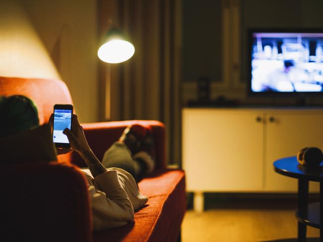 Watching TV while scrolling on a mobile phone is common in most households these days. Picture: istock