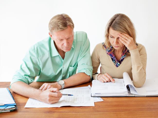 Middle aged couple sitting together at table and going through monthly expenses bills. They are experiencing stress. Picture: iStock.