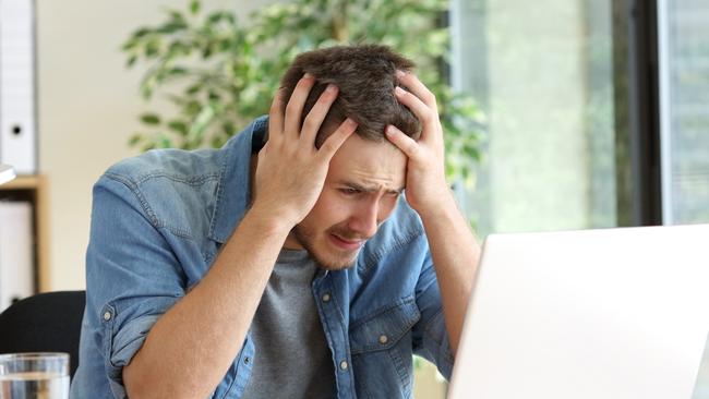 A stressed man at his computer after just realising he has been scammed. Picture: iStock.