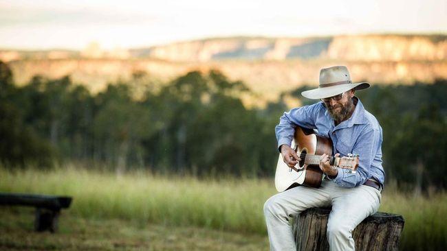 Bruce Mayne on the land he loves with his guitar. Photo Contributed / Rockhampton Morning Bulletin