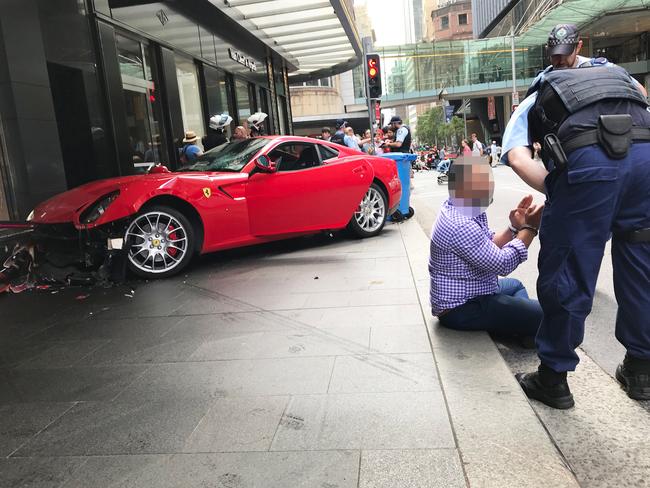 The 41-year-old man sits handcuffed on the footpath. Picture: Bob Barker