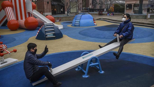 A Chinese couple wear protective masks as they sit on a ride at a shopping mall in Beijing, China. Picture: Getty Images
